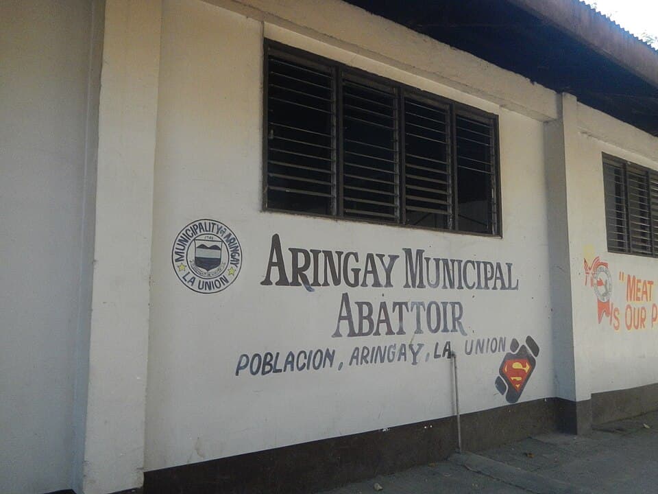 The painted wall sign of the Aringay Municipal Abattoir in Poblacion, Aringay, La Union, a concrete government slaughterhouse building with barred windows