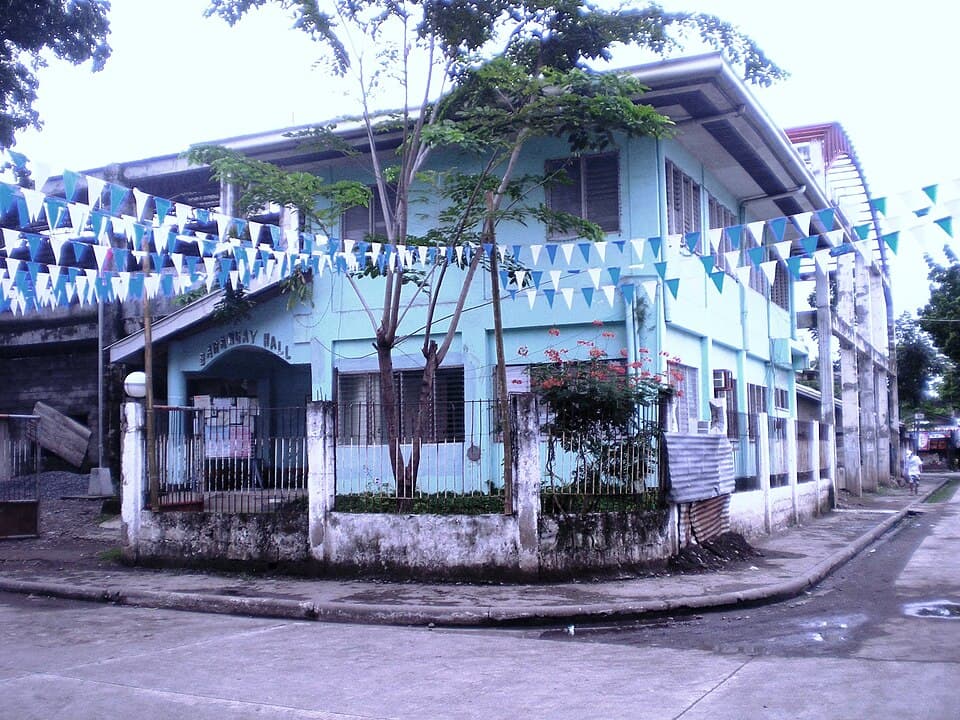 The two-storey barangay hall of Barangay Agusan in Cagayan de Oro City, decorated with blue and white bunting, shown as a representative example of a Mindanao barangay hall