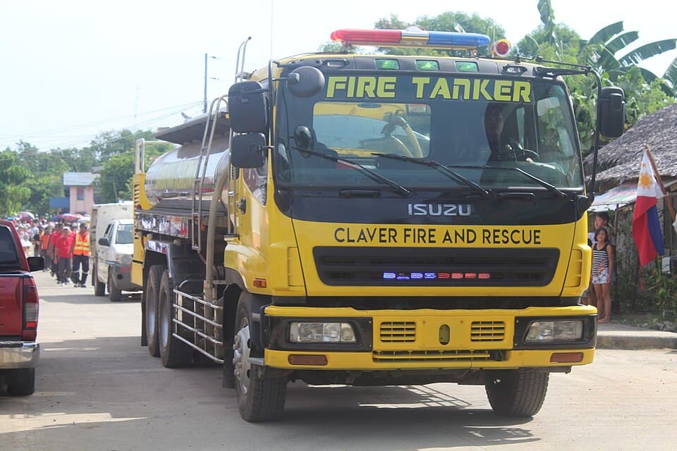 A yellow Isuzu fire tanker marked Claver Fire and Rescue on a street in Claver, Surigao del Norte, during a 2018 Independence Day event