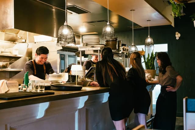 A restaurant kitchen and counter, staff preparing orders for customers