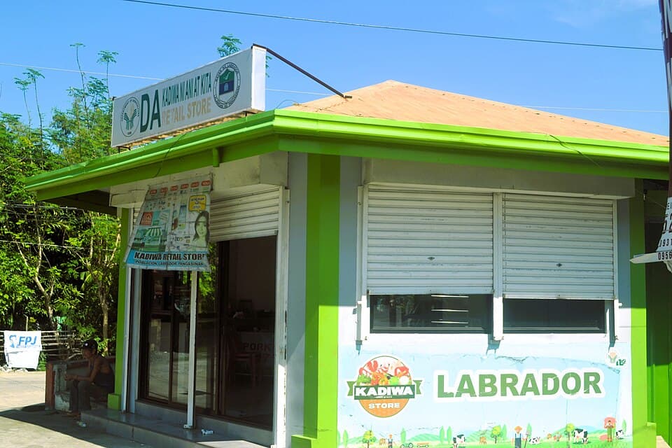 A green-and-white Department of Agriculture KADIWA store kiosk with its shutters closed and the word Labrador painted on its wall, not in Bislig