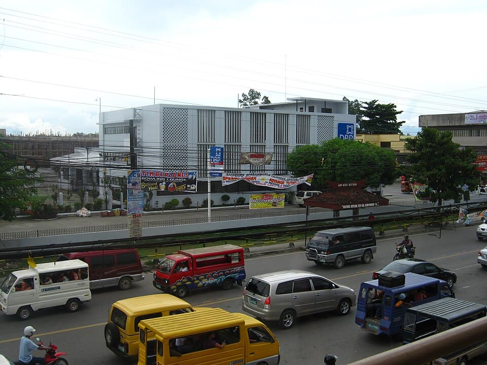 The Development Bank of the Philippines branch building in Butuan City, seen across a busy road with multicabs and vans