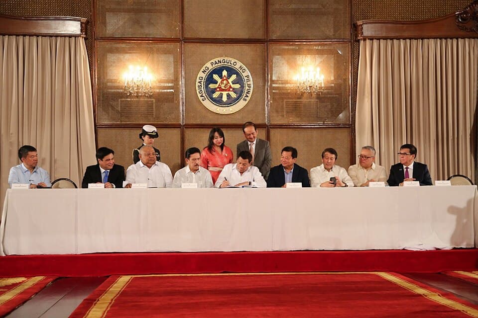 President Rodrigo Duterte, seated at a long table with government officials in Malacañang, signs the Ease of Doing Business and Efficient Government Service Delivery Act of 2018