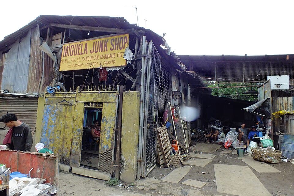 A junk shop with a yellow signboard and sacks of collected scrap under a tin roof in Mandaue City, Cebu, shown as a representative example of a Philippine junk shop