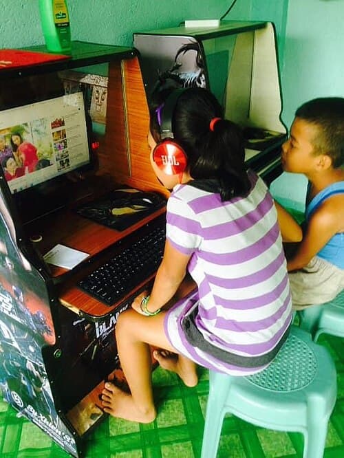 Children using a coin-operated piso Wi-Fi vending kiosk in the Philippines