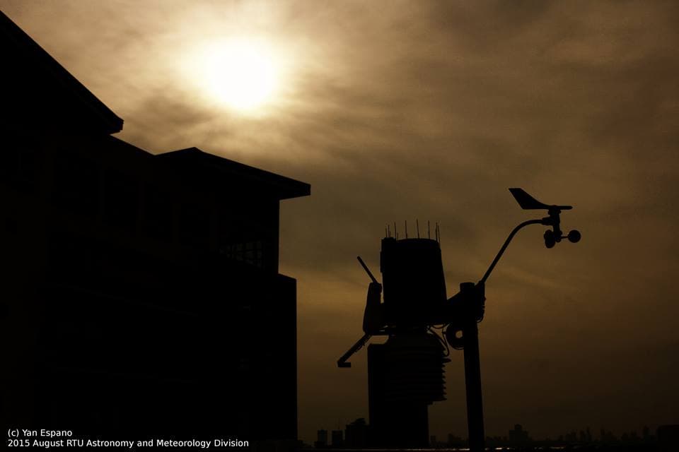 Silhouette of an automated weather station with a wind vane and sensor mast beside a building, at Rizal Technological University in Mandaluyong (not the Bislig site)