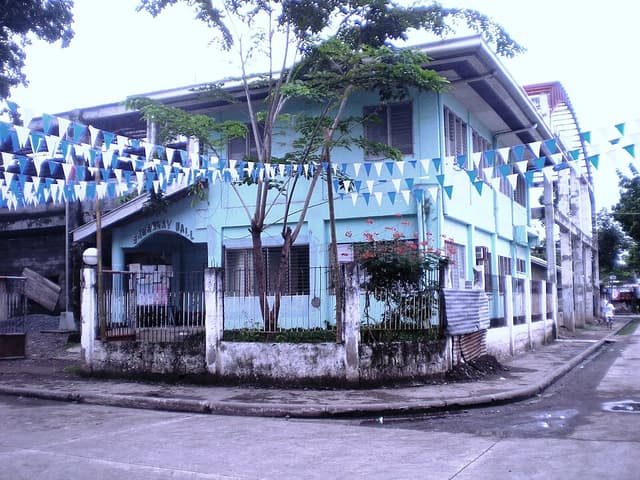 The two-storey barangay hall of Barangay Agusan in Cagayan de Oro City, decorated with blue and white bunting, shown as a representative example of a Mindanao barangay hall