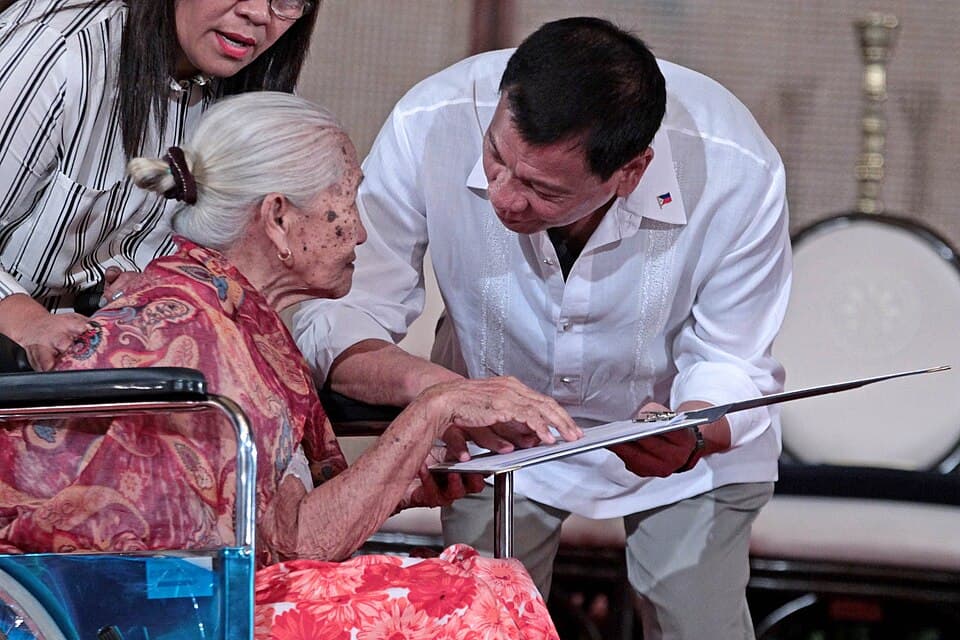 Former President Rodrigo Duterte shows the signed rules of the Centenarians Act of 2016 to 108-year-old Lourdes Marquez of Caloocan City at Malacañan in September 2016