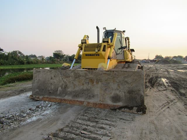 A yellow Komatsu bulldozer with its blade lowered on a dirt road construction site in Santo Tomas, Pampanga, at dusk
