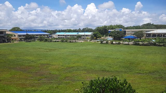 The open field of the North Eastern Mindanao State University main campus in Tandag City, with school buildings in the background, photographed from a rooftop