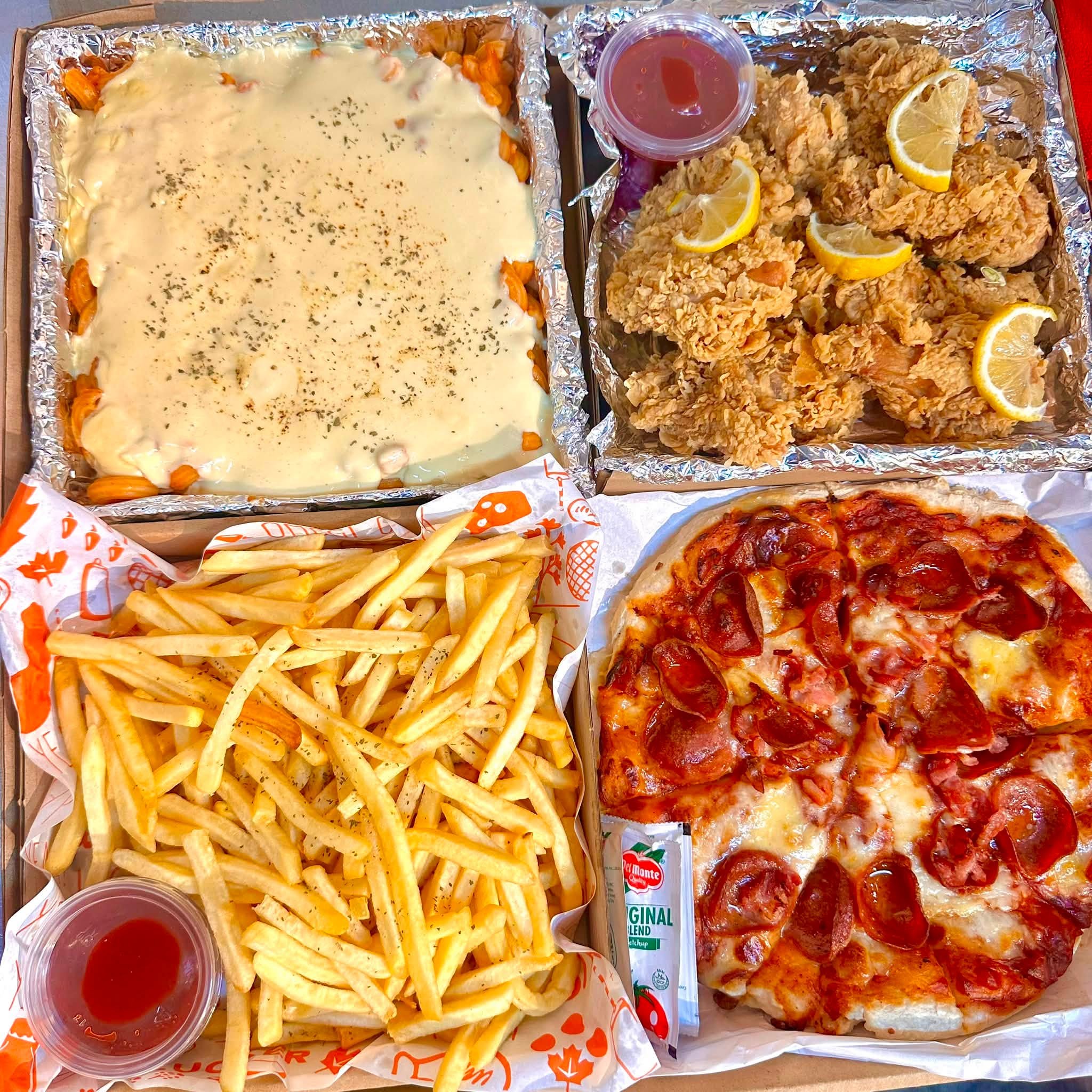 A Food in a Box meal package with fried chicken, pizza, fries, and a creamy dish
